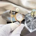 Elegante Perlen Armreif Uhr für Damen, Roségold Quarzuhr mit funkelnden Strasssteinen. - Perlmutt-Zifferblatt / Roségold