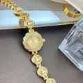 Goldfarbene Strass-Quarz-Armbanduhr Detailansicht mit elegantem Blumen-Charm Design. - Gold