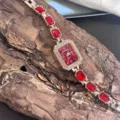 Detailaufnahme der eleganten rechteckigen Strass Quarz Damenuhr mit rotem Edelstein Armband. - Rot