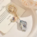 Détail de porte-clés doré élégant avec pendentif coquillage en acrylique dégradé coloré. - Gris