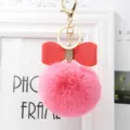 Close up view of pink fluffy pom pom keychain featuring red leather bow accessory detail - 8cm Pompom / Deep Pink