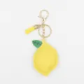 Vista detallada del bonito llavero de cuero con diseño de limón amarillo y herrajes dorados. - Limón con Borla