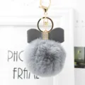 Grey faux fur pom pom keychain detail featuring a leather bow and metal hardware clasp. - 8cm Pompom / Medium Grey
