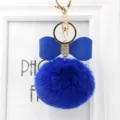 Detailed close-up of a vibrant blue faux rabbit fur pom pom keychain with a bow charm. - 8cm Pompom / Sapphire Blue