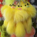 Close up detail of yellow fluffy fur pom pom keychain with cute bow and bead eyes charm. - 20x6cm / Yellow