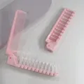 Vue détaillée du peigne double pliable portable en rose, montrant dents fines et picots de massage. - Emballage Individuel / Rose