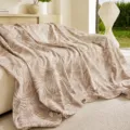 Detailed view of the jacquard sofa cover blanket with elegant tropical leaf pattern for living room - 115x70 / Light Mocha