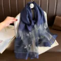 Nahaufnahme des dunkelblauen Organzaschals mit Perlenstickerei und feinen floralen Mustern. - Marineblau