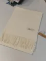 Detailaufnahme eines einfarbigen Kaschmir-Imitat-Schals mit Fransen für den Winter. - Creme