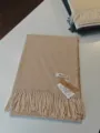 Detailansicht des einfarbigen Kunstkaschmir-Winterschals mit eleganten Fransen und Etikett. - Haferflockenfarbe