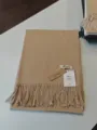 Nahaufnahme eines weichen Kaschmir-Gefühl Winterschals mit Fransen und Markenschild. - Kamelbeige