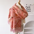 Close-up of pink and orange patterned winter knit scarf with cozy tassels and texture. - Pink