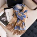 Detailed view of the blue and brown floral patterned tassel cashmere-feel scarf on sofa setup. - Dark Khaki
