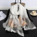 Detailansicht eines weißen Seidenschals mit exquisiter Blumenstickerei und Perlen. - Weiß