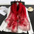 Detailed view of red embroidered silk scarf with delicate floral patterns and shimmering edges. - Burgundy