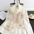 Nahaufnahme des eleganten weißen Seidenschals mit filigranen rosa Blumenmustern im Detail. - Weiß