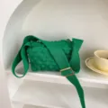 Detailaufnahme der grünen Strick-Crumple-Umhängetasche mit breitem Gurt und Schnalle. - Dunkelgrün