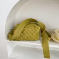 Grüne gestrickte Umhängetasche Detailansicht mit strukturierter Blasenoptik und breitem Gurt. - Kurkuma