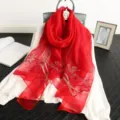 Detail view of red silk embroidered scarf with sparkling rhinestones and floral design. - Red