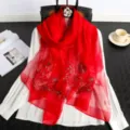 Red silk embroidered scarf detail view showcasing delicate floral craftsmanship and premium texture. - Red
