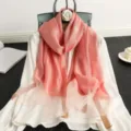 Detailed view of the elegant pink silk wool scarf with golden grid texture, draped nicely. - Peach Pink