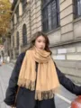 Nahaufnahme eines gemütlichen, einfarbigen Kamel-Winterschals mit Fransen, Streetstyle. - Beige