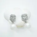 Detailed close-up of exquisite cubic zirconia pearl drop earrings displayed on a white cloud prop. - Stud Earrings-Acrylic Bead / Silver