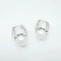 Close-up detail of silver metal hoop earrings with glossy white pearl charms, stylish design. - Earrings - Silver (Acrylic Bead)