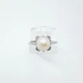 Primer plano detallado de un anillo de perlas con circonitas y una elegante montura metálica. - Anillo / Cuentas acrílicas / Plateado