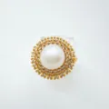 Detailaufnahme des eleganten Perlenrings mit vergoldeter Fassung und funkelnden Zirkoniasteinen. - Ring / Acrylperlen / Gold