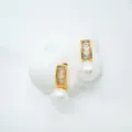 Nahaufnahme eleganter goldener Ohrringe mit Kristallen und weißen Perlen, schicker Schmuck. - Ohrstecker / Naturperle / Gold