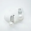 Detailaufnahme eleganter silberner Ohrringe mit funkelnden Diamanten und weißen Perlen. - Ohrstecker / Acrylperlen / Silber
