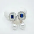 Close-up detail of vintage geometric rectangular blue crystal pearl earrings with white enamel frame. - Sapphire Stud Earrings (Acrylic Bead) / Silver