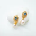 Detalle en primer plano de pendientes colgantes de perla y cristal azul vintage. - Pendientes de botón / Perla Natural / Dorado