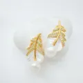 Close-up detail of elegant gold-plated feather pearl earrings with mother-of-pearl and zircon. - Stud Earrings / Natural Pearl / Gold