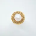 Close-up detail of luxury gold-plated pearl and cubic zirconia sunburst pendant accessory. - Ring / Acrylic Beads / Gold