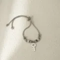 Vista detallada de una pulsera de cadena de serpiente plateada con colgante de llave. - Llave de Plata