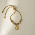 Pulsera ajustable de acero inoxidable dorado con colgante de candado en detalle elegante. - Dorado Candado