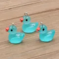 Close-up detail of cute turquoise resin duck pendant charm with metal loop and orange beak. - Blue