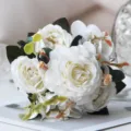 Primo piano dettagliato di bouquet di fiori di peonia rosa artificiale bianca con foglie verdi. - Bianco