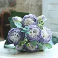 Detailed close-up of purple artificial peony bouquet, exquisite flower heads and green leaves. - Violet
