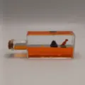 Fluedische Deko Schreibtisch Spielzeug mit Dinosaurier Vulkan Figur in orangerem Ölfläschchen. - Viereckige Flasche Dinosaurier