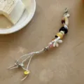 Detailed view of handmade beaded phone charm featuring colorful floral pendants and metal details. - Berlin Girl / 1 Piece/Pack