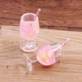 Nahaufnahme des Miniatur-Harz-Cocktailglas-Anhängers, rosa Flüssigkeit mit Zitrone und Strohhalm. - Dunkelrosa