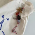 Handmade woven phone charm and bag pendant with colorful braided cords and flower beads detail. - Woven Flowers / Coffee
