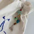 Detailed view of handmade beaded braided phone charm and bag pendant with green floral design. - Woven Flowers / Green