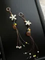 Handcrafted beaded phone charm close-up detail showcasing intricate floral pendants and tassels. - Pine Forest Floral Charm