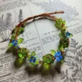 Handgemaakte macrame kristal en bloem armband detail, groene glazen kralen koord. - Klein Blauw Bloemen Haarelastiek
