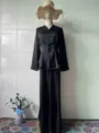Detail view of the black satin long sleeve top and matching skirt set, elegant design. - Black