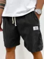 Corduroy shorts detail view showing the texture fabric, white patch and drawstring. - S / Bottoms / Black